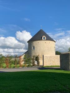 TurquevilleGîte Manulau的一座大型砖砌建筑,在草地上建有塔楼