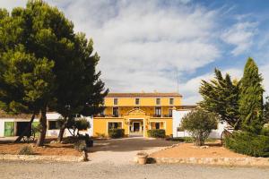 Caudete de las FuentesHotel rural Entreviñas的前面有树木的黄色建筑