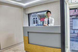 伊斯坦布尔Florina Hotel的一张站在一个房间柜台上的男人的照片