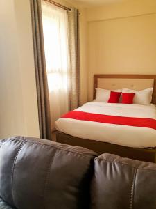 NarokWalabi Mara Hotel的一间卧室配有一张带红色枕头的床和一张沙发