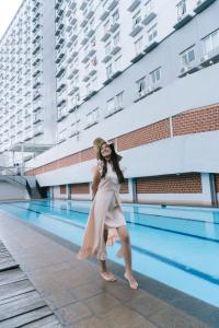 玛琅Apartemen Soekarno Hatta by C Management 2的身着连衣裙的女人站在游泳池旁