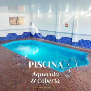 伊瓜苏伯多禄宫酒店的一座游泳池,位于一座建筑物的中间,上面写着“pisgana”字样