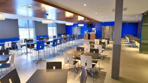 沃德勒伊多里翁沃德勒伊多里翁智选假日酒店的餐厅设有桌椅和蓝色的墙壁