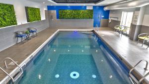 沃德勒伊多里翁沃德勒伊多里翁智选假日酒店的一座蓝色的游泳池,在建筑里摆放着椅子