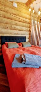 罗瓦涅米Cozy Log Cabin by Invisible Forest Lodge的小木屋内一间卧室,配有红色的床