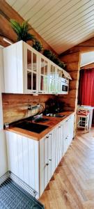 罗瓦涅米Cozy Log Cabin by Invisible Forest Lodge的厨房配有白色橱柜和台面