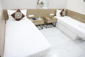 海得拉巴SwanSuites Gachibowli的配有一张桌子和两张床的房间内的两张床