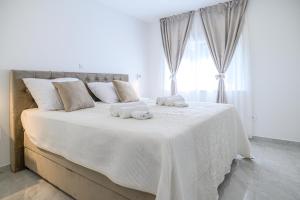 斯普利特Luxury rooms Green and Gold Split的白色卧室配有一张大床和毛巾