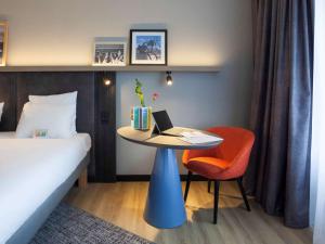 斯海弗宁恩ibis Styles Den Haag Scheveningen的酒店客房配有一张床和一张带笔记本电脑的桌子