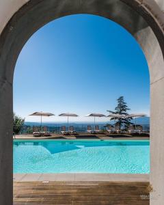 卢卡Villa Guinigi Dimora di Epoca Exclusive Residence & Pool的一个带椅子和遮阳伞的拱下游泳池
