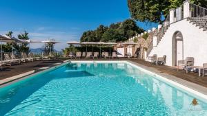 卢卡Villa Guinigi Dimora di Epoca Exclusive Residence & Pool的一座带椅子和遮阳伞的游泳池位于一座建筑旁边