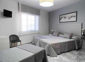 桑亨霍Hotel Florida Mar的一间卧室设有两张床、一把椅子和一个窗户。