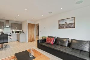 New Southgate1-Bed Spacious Flat, North London, 15 Minutes to Central的一间带黑色真皮沙发的客厅和一间厨房