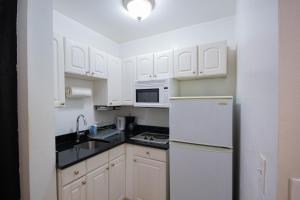 纽约一卧室超级公寓的厨房配有白色橱柜和白色冰箱。