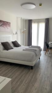 卡里翁德洛斯孔德斯Hostal Comfort Suites的卧室配有一张白色大床,铺有木地板