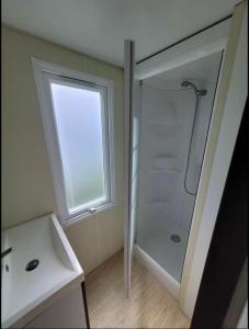 Biville-sur-MerCamping le Clos Savoye的带淋浴和盥洗盆的浴室以及窗户。
