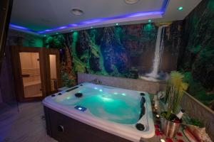 阿拉贡省阿拉马APARTAMENTO ESTRELLA SAUNA SPa JACUZZI的浴室配有浴缸及瀑布壁画