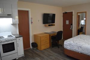 卡斯尔加Canadas Best Value Inn & Suites-Castlegar的酒店客房配有一张床、一张书桌和一间厨房。