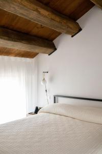 Urbisaglia罗卡达小屋酒店 的卧室配有白色床和木制天花板