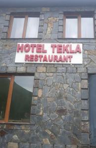 乌树故里Hotel Tekla的石头建筑上的酒店餐厅标志