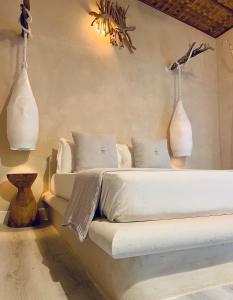 ThinadhooThari Fushi Luxury Maldivian Experience - All Inclusive的卧室配有一张壁挂两花瓶的床