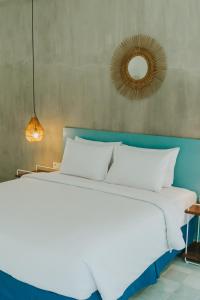 龙目岛库塔Birru Inn的一张配有白色床单和镜子的大床