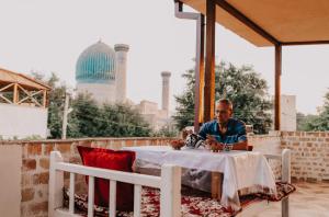 撒马尔罕迪秀达酒店的坐在庭院桌子上的男人