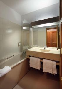 圣莫里斯堡奥坦蒂克酒店的一间带水槽、浴缸和镜子的浴室