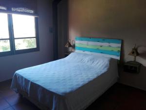 圣拉斐尔Cabañas La Cosecha的一间卧室配有一张带蓝色床头板的床和两个窗户