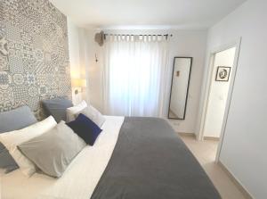 马拉加La Tierra Sur apartment Malaga Center的一间卧室配有一张带蓝白色枕头的大床