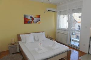 斯雷姆斯卡米特罗维察Angellina Apartmani的一间卧室配有一张带白色床单的床和一扇窗户。