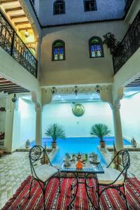 马拉喀什Riad Milouda的配有桌椅和游泳池的客房