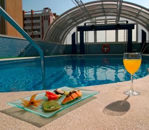 塞维利亚塞维利亚顶点酒店的游泳池旁的一杯食物和一杯葡萄酒
