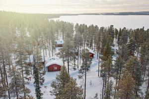 穆奥尼奥Mökki Jerisjärven rannalla的雪林中间的红色小屋
