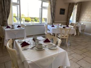 克利夫登Ardmore House的餐厅设有白色的桌椅和窗户。
