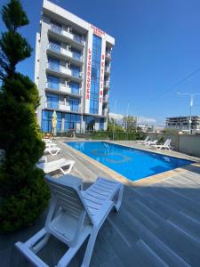 巴统Hotel Skyline Batumi的酒店游泳池设有躺椅,酒店大楼