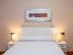 潘普洛纳管理客房及套间酒店的卧室配有一张白色的床,上面有一张图画