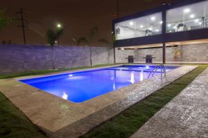 蒙特雷CHN Hotel Monterrey Aeropuerto, Trademark by Wyndham的一座游泳池,在晚上在建筑物前