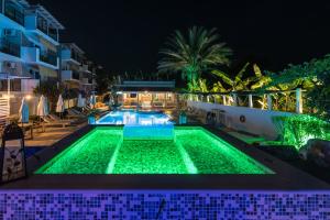 阿凯松Iniohos Zante Hotel & Suites的夜晚带绿灯的游泳池