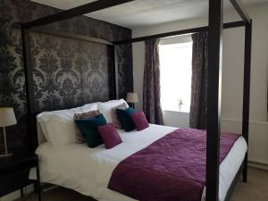 布雷肯Ty Helyg Guest House的一间卧室配有一张带紫色床单的天蓬床