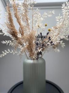 RødekroHotel Røde-Kro的一张桌子上装有干植物的白色花瓶