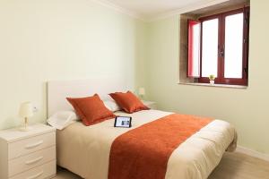 帕德隆A Casa Antiga do Monte Apartamentos Turísticos - Lestrove的白色卧室配有带橙色枕头的大床