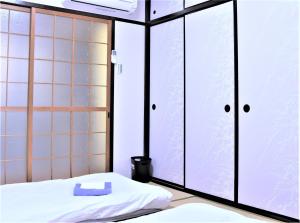 大阪Kamiyama Mansion - Vacation STAY 11596的一间设有床铺和玻璃门的房间