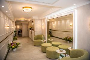 鲁塞Arletti Hotel的一间设有绿色椅子和桌子的等候室,并种植了鲜花