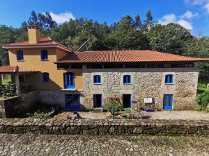 CerdalQuinta Estrada Romana - Albergue de Peregrinos的一座大型石头房子,在院子里设有蓝色窗户