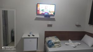 阿帕雷西达Pousada Quarto completo ar,wi fi e garagem gratuita的客厅配有沙发和墙上的电视