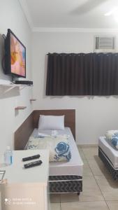 阿帕雷西达Pousada Quarto completo ar,wi fi e garagem gratuita的一间设有床铺和电视的房间
