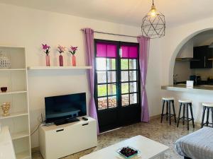 阿索马达Vivienda vacacional Julia的一间带电视和带粉红色窗帘的门的客厅