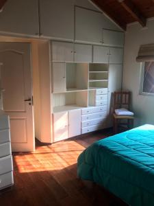 圣佩德罗Quinta El Molino的卧室配有白色橱柜、一张床和一把椅子