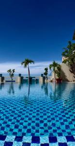 美奈美奈山背包客旅舍的一座种植了棕榈树和大海的蓝色游泳池